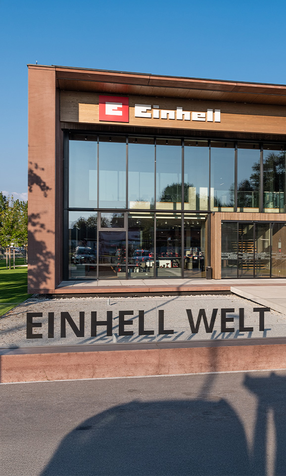 Einhell World: edifício moderno da empresa com o logótipo da Einhell e um grande grupo de funcionários.