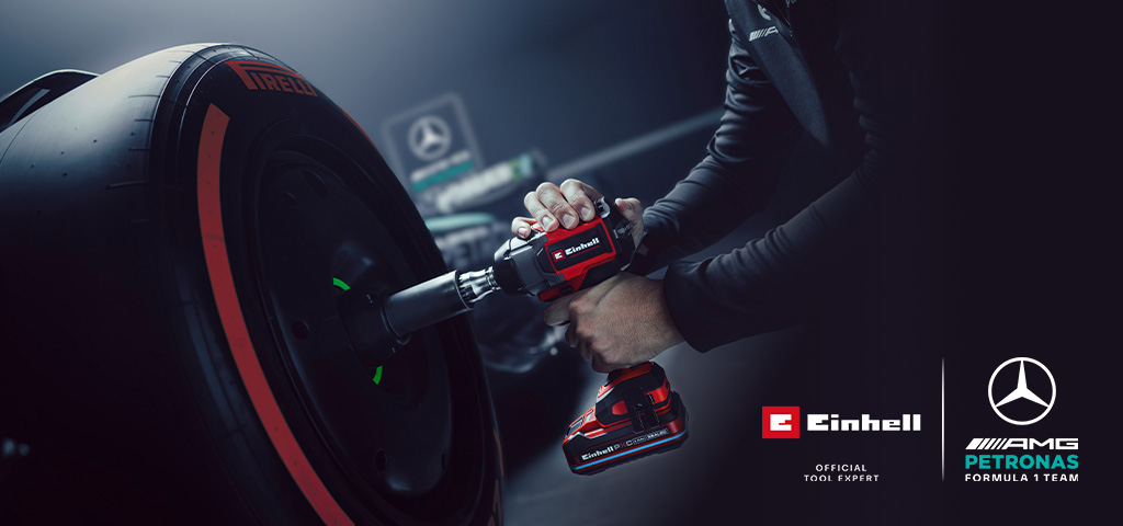 Chave de impacto sem fio Einhell em uso numa roda de carro, com o branding e o logótipo de parceria da equipa Mercedes-AMG Petronas de Fórmula 1