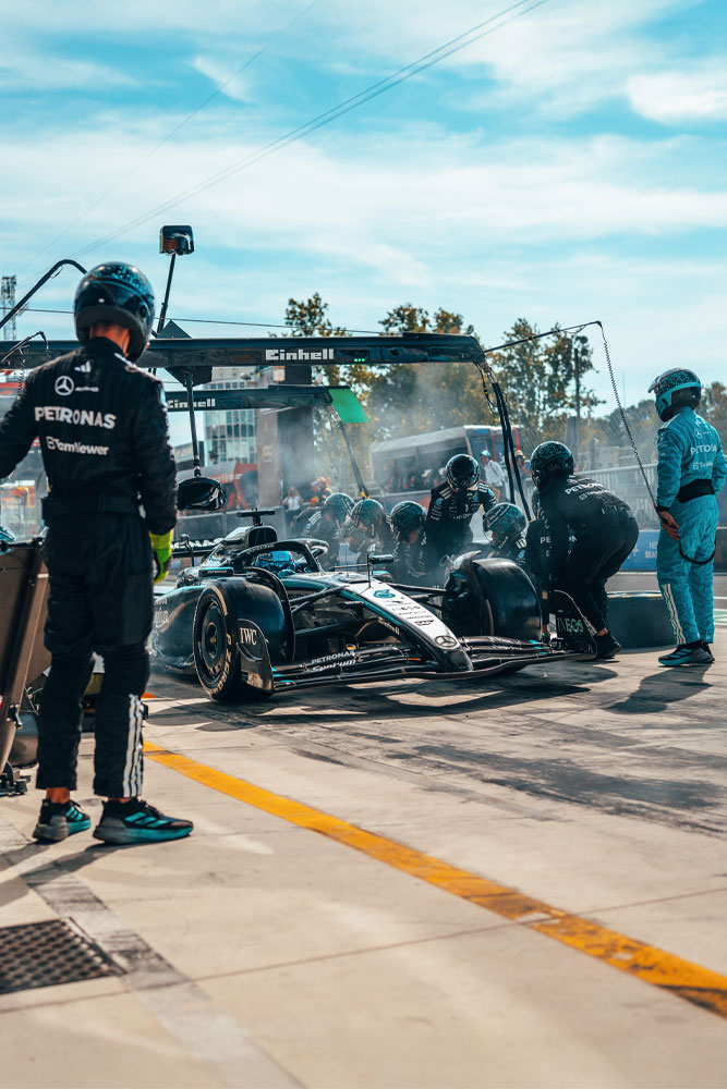Um pit stop de alta intensidade para a equipe Mercedes-AMG PETRONAS Formula One. A equipe está em ação, trocando pneus e verificando o carro sob a estrutura com a marca Einhell.