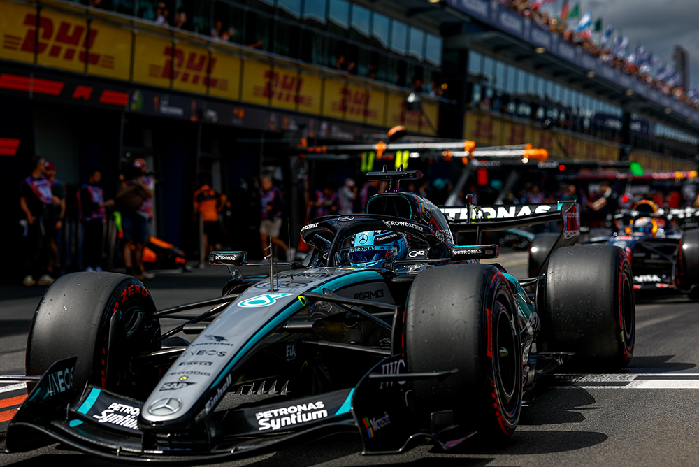 Carro de Fórmula 1 no pit lane cercado pela equipe antes da largada.