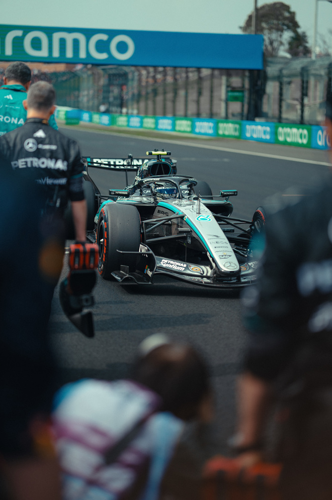 Carro F1 Mercedes no pit lane rodeado pela equipa