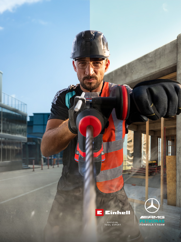 Um mecânico com equipamento de proteção a perfurar com uma ferramenta elétrica num estaleiro de construção.