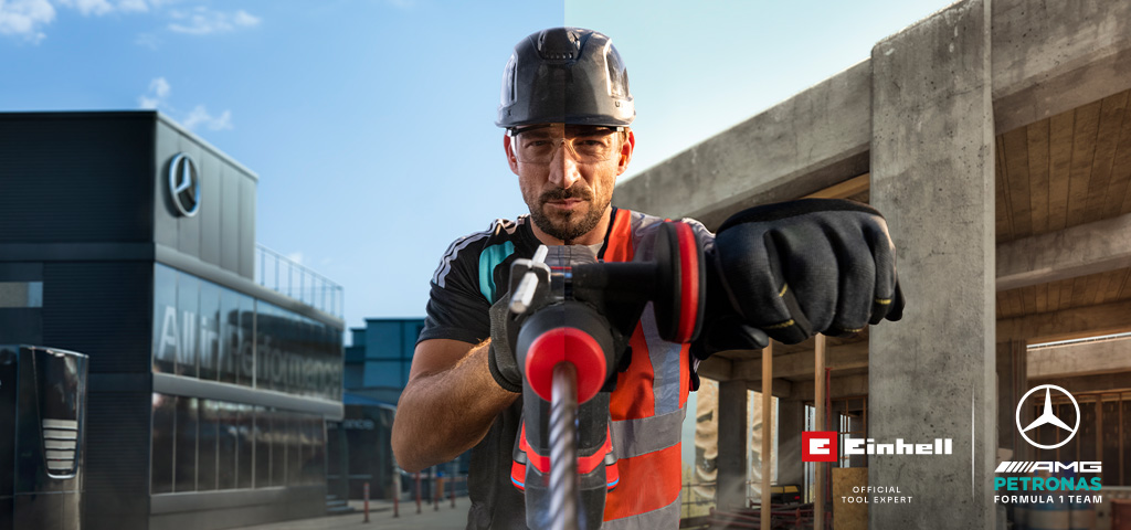 Um mecânico, equipado com equipamento de proteção, a perfurar com uma ferramenta elétrica num estaleiro de construção.