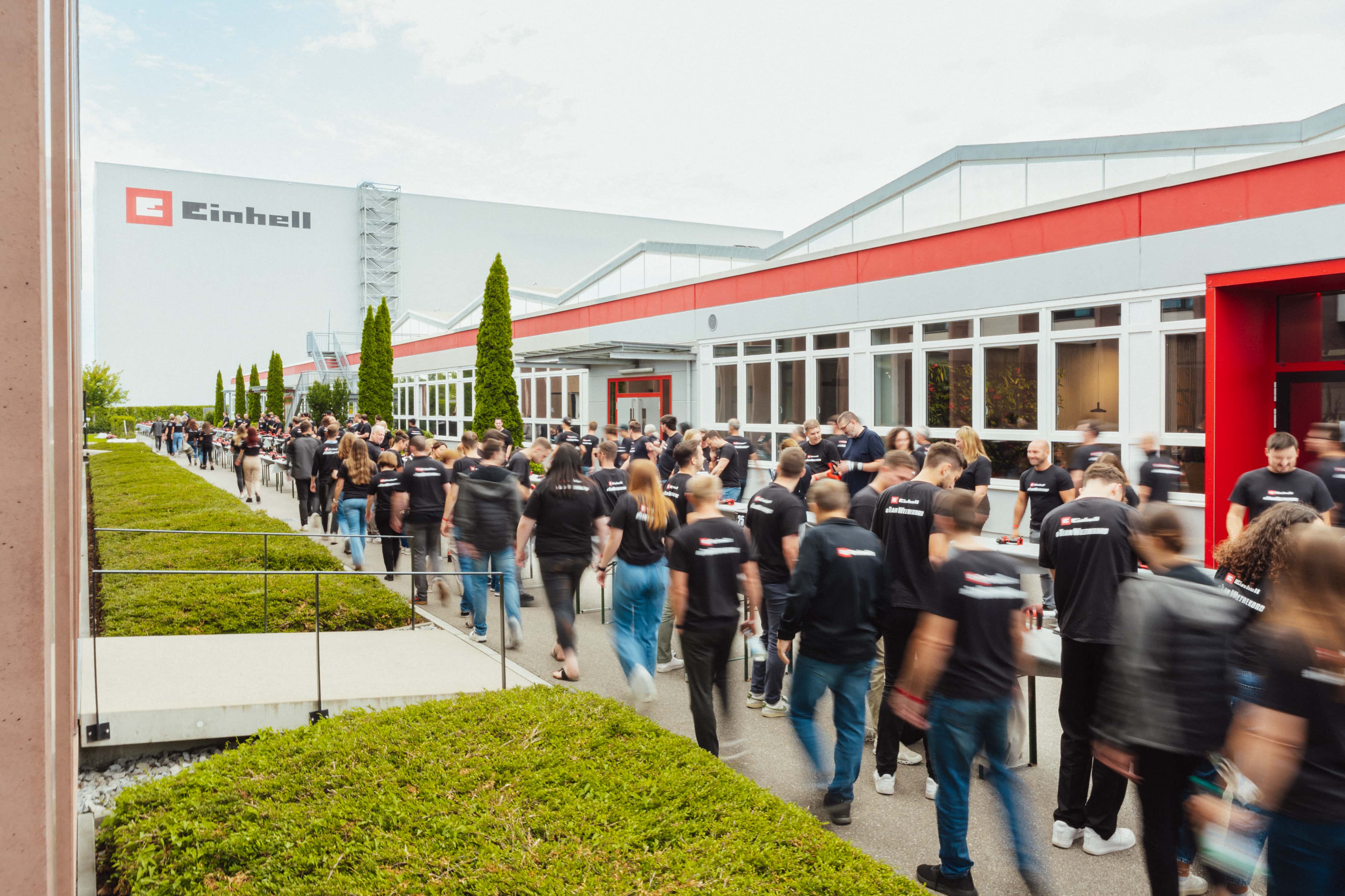 Cadeia humana em movimento durante o revezamento de baterias com baterias Einhell em frente ao edifício da empresa.