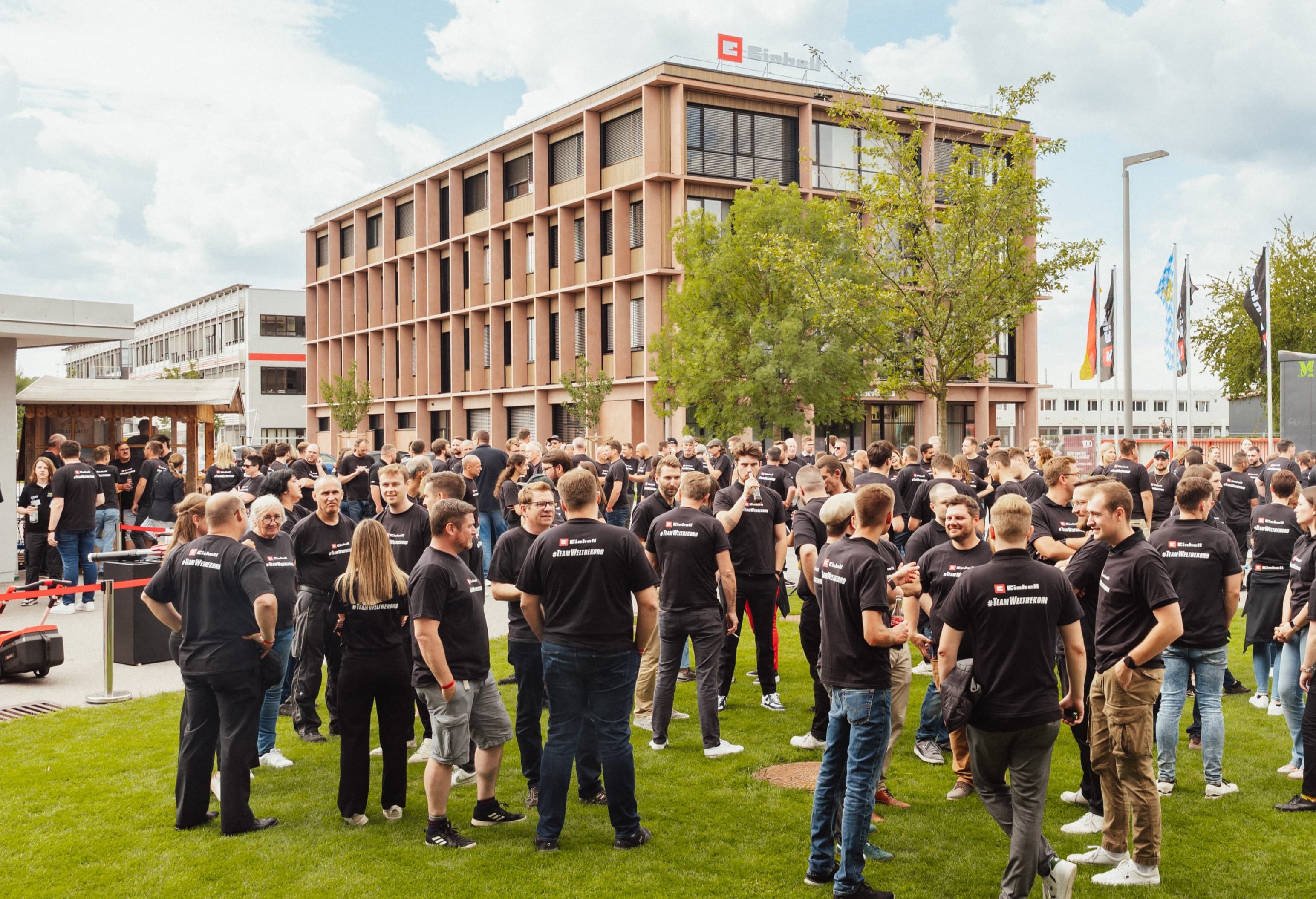 Muitas pessoas com t-shirts pretas da Einhell com o slogan "#TeamWeltrekord" reúnem-se nas instalações da empresa.
