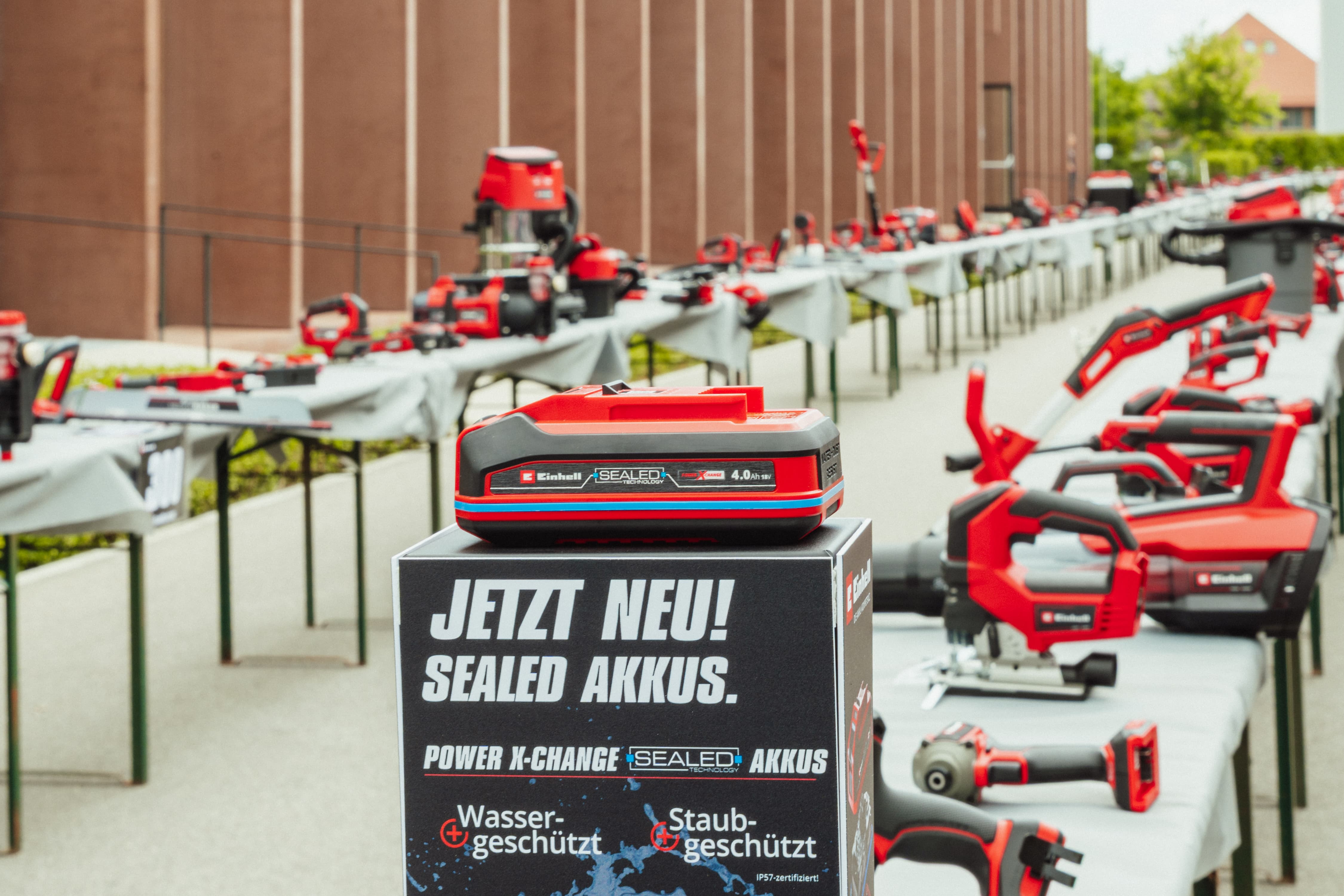 Uma bateria Einhell SEALED Power X-Change 4.0 Ah em exposição com a inscrição: “JETZT NEU! SEALED AKKUS”.