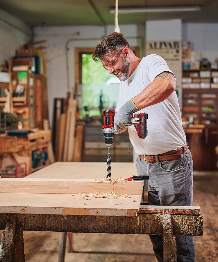 A man using the cordless drill in his workshop. 